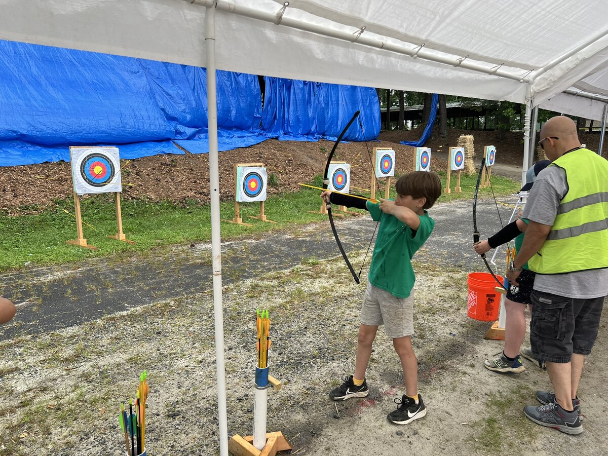 Pack 199 scouts practicing archery at an outdoor range.